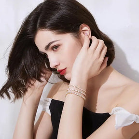 Woman with dark hair in black top showcasing 18K Gold Plated Tennis Bracelet with Lab Grown Diamonds