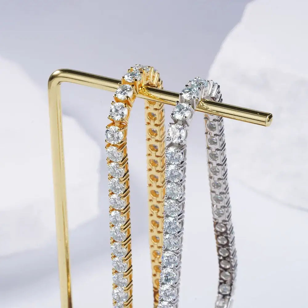 Three diamond tennis bracelets in gold and silver tones on display, featuring lab grown diamonds