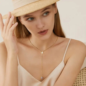 Woman in a straw hat showcasing a 6.5mm Lab Grown Diamond Butterfly Pendant necklace