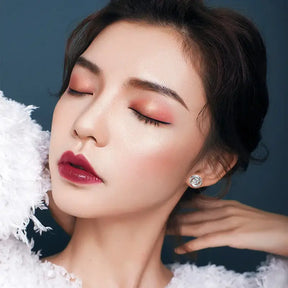 Close-up portrait of a woman with dramatic makeup showcasing silver stud earrings with lab grown diamond