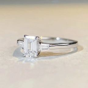 Engagement ring featuring an emerald cut moissanite in a sterling silver band