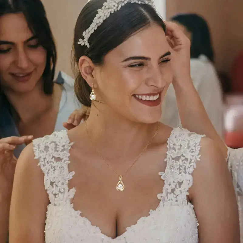 Smiling bride in lace dress with floral headpiece showcasing a sterling silver pearl jewelry set