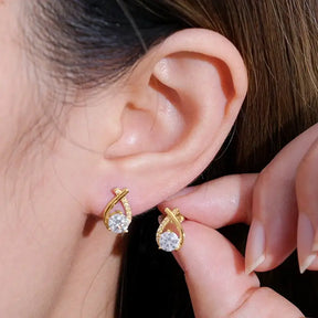 Gold fishtail cross diamond earrings featuring teardrop-shaped diamond stones