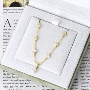 Delicate gold necklace with crystal accents beside Four-Leaf Clover Bracelet with Lab Grown Diamonds