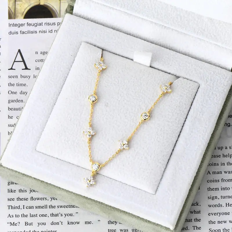 Delicate gold necklace with crystal accents beside Four-Leaf Clover Bracelet with Lab Grown Diamonds