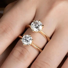 Two diamond solitaire engagement rings on a finger showcasing Gold Plated Moissanite style