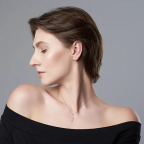 Profile view of a person in a black off-shoulder top wearing a diamond curve pendant