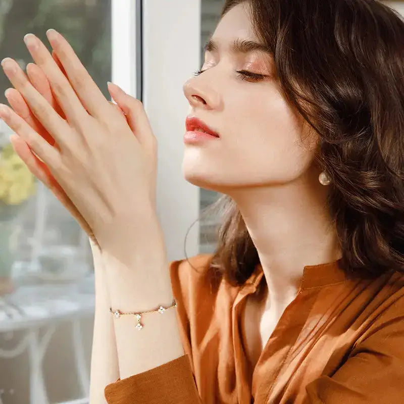 Young woman with wavy brown hair models moissanite diamond bracelet in four-leaf flower design