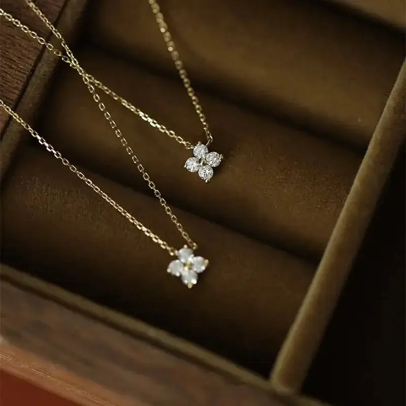 Two gold necklaces with diamond flower pendants on sterling silver chains