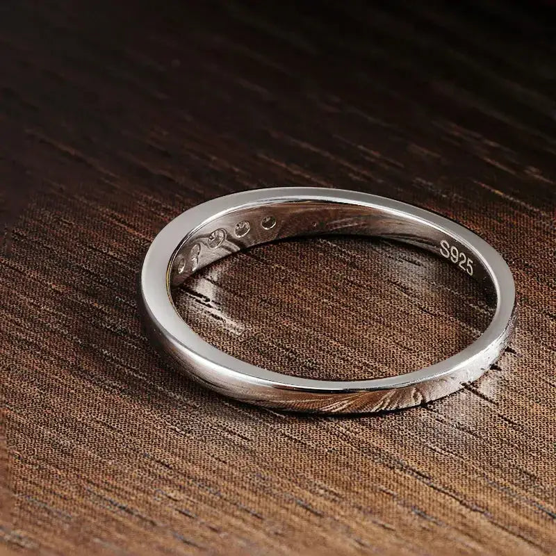 Simple silver band ring on textured surface showcasing Moissanite Rings in Sterling Silver