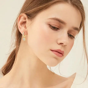 Young woman with light brown hair showcasing lab grown diamond drop hoop earrings