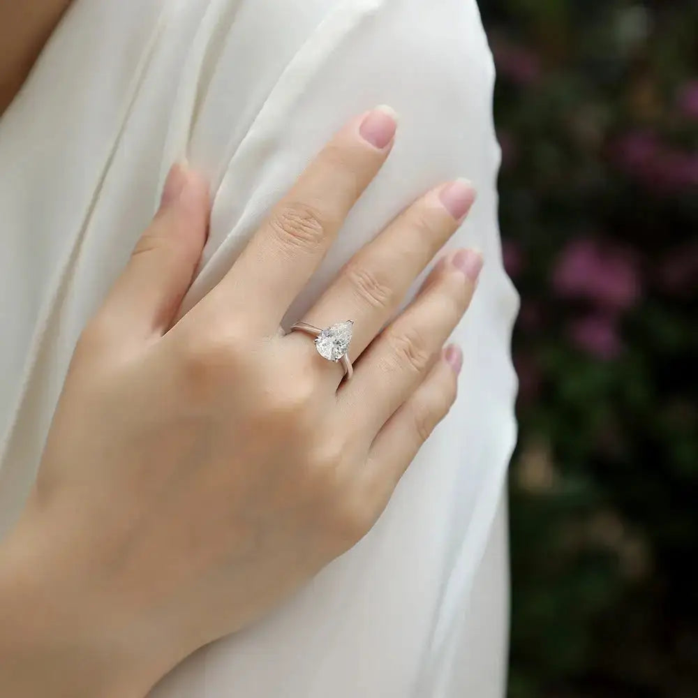 Pear cut moissanite diamond ring displayed on a woman’s hand in sterling silver