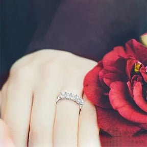 Diamond ring on finger beside red rose, showcasing Princess Cut Moissanite Wedding Band