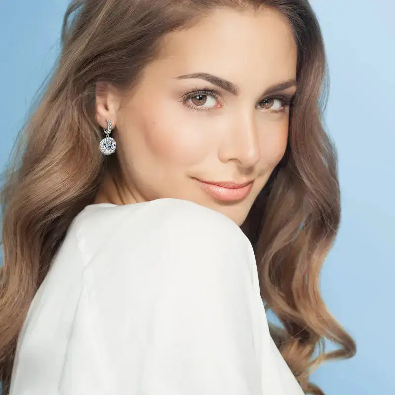 Woman with wavy brown hair showcasing Moissanite Drop Hoop Earrings in 925 Silver