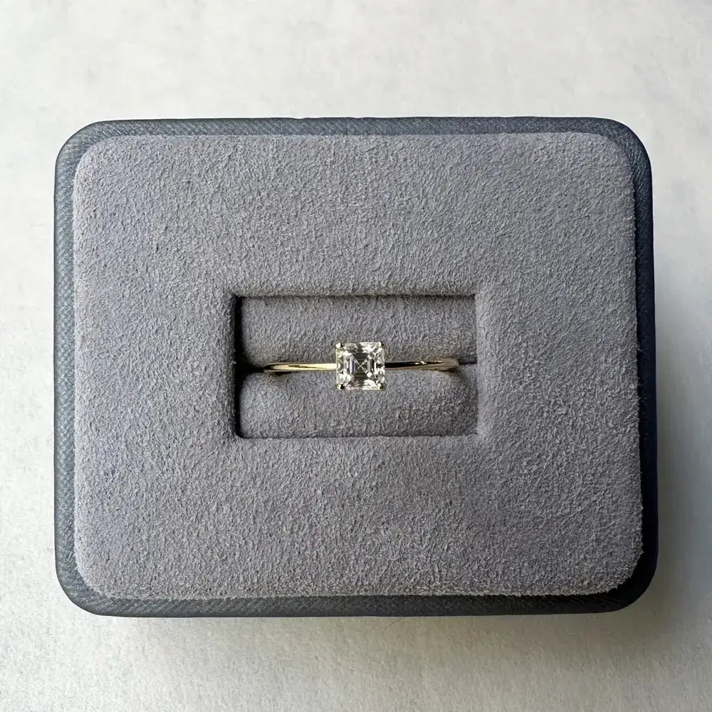 Diamond engagement ring featuring a solitaire emerald-cut stone on a gold band